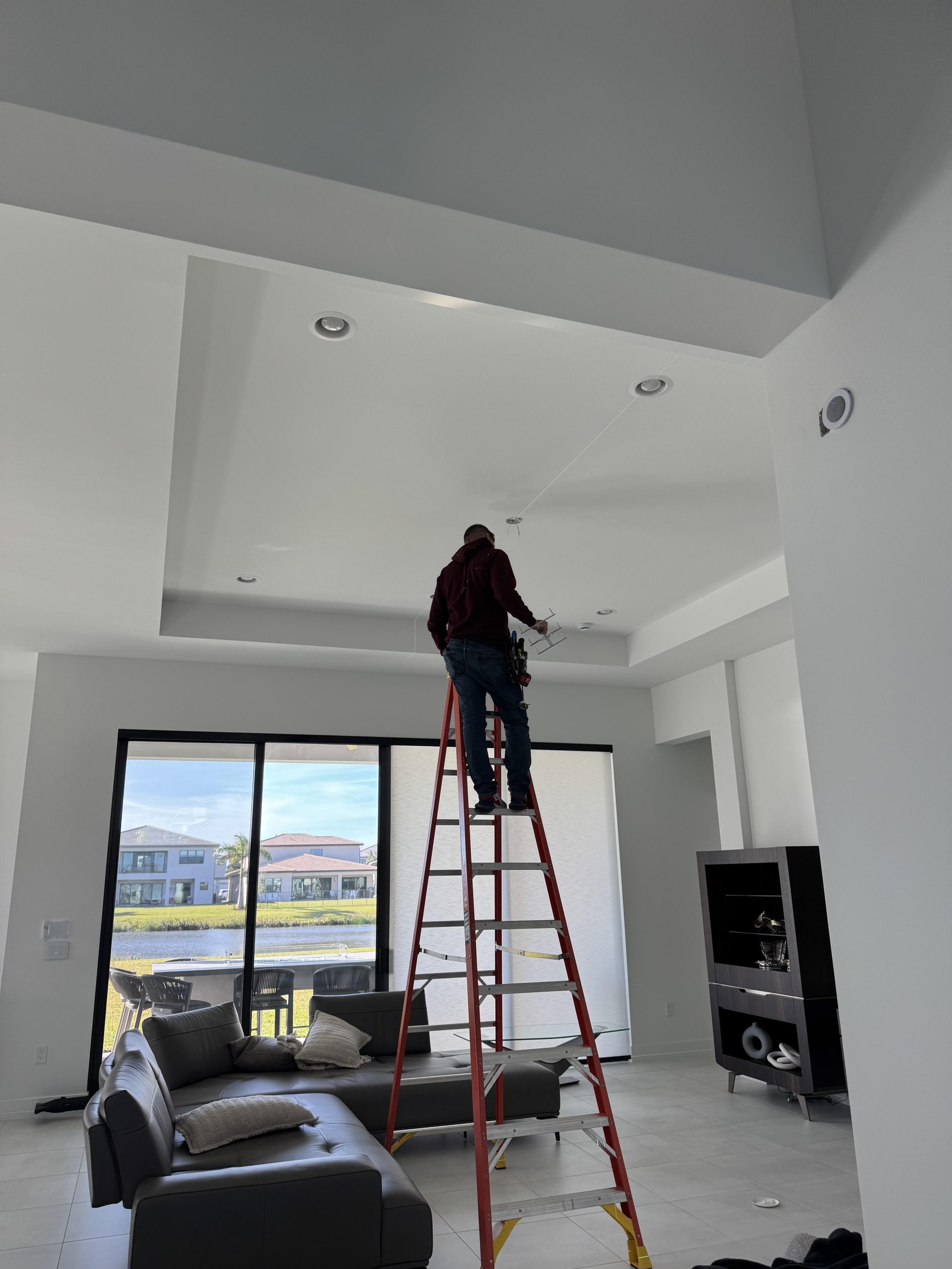 A man stands on a ladder in a well-lit living room